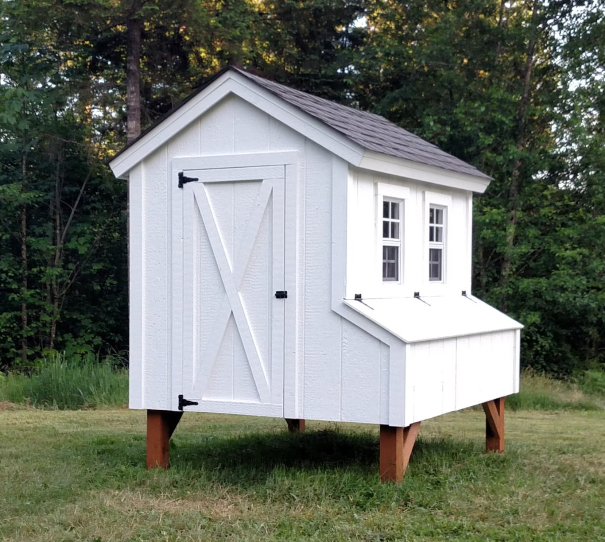 A white, country-style chicken coop elevated off the ground.