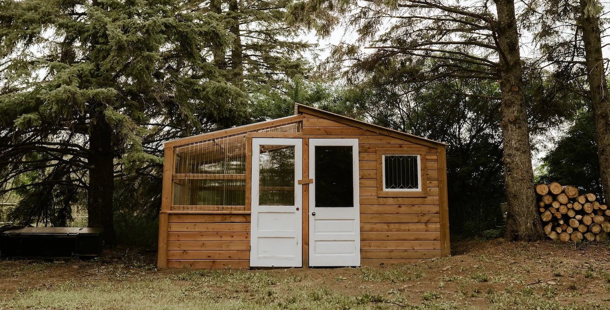 Combination greenhouse shed in a rustic style with white doors.