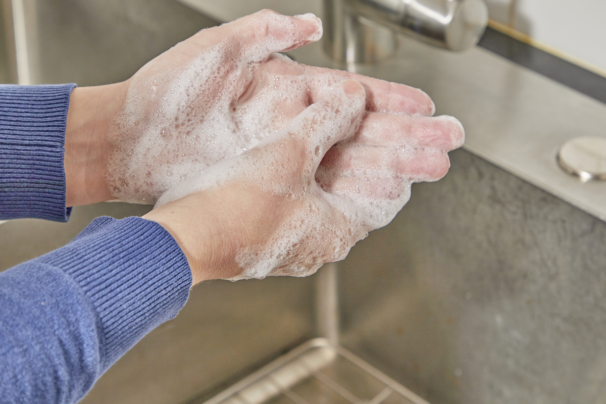 Woman washes her hands with foamy soap under a running faucet.