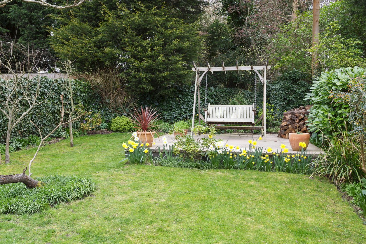 Backyard retreat with wooden swing on wooden patio.