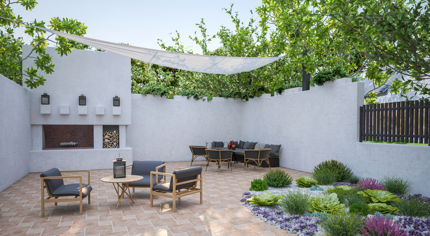 A backyard with patio flooring, stucco walls, and drought-tolerant plants.