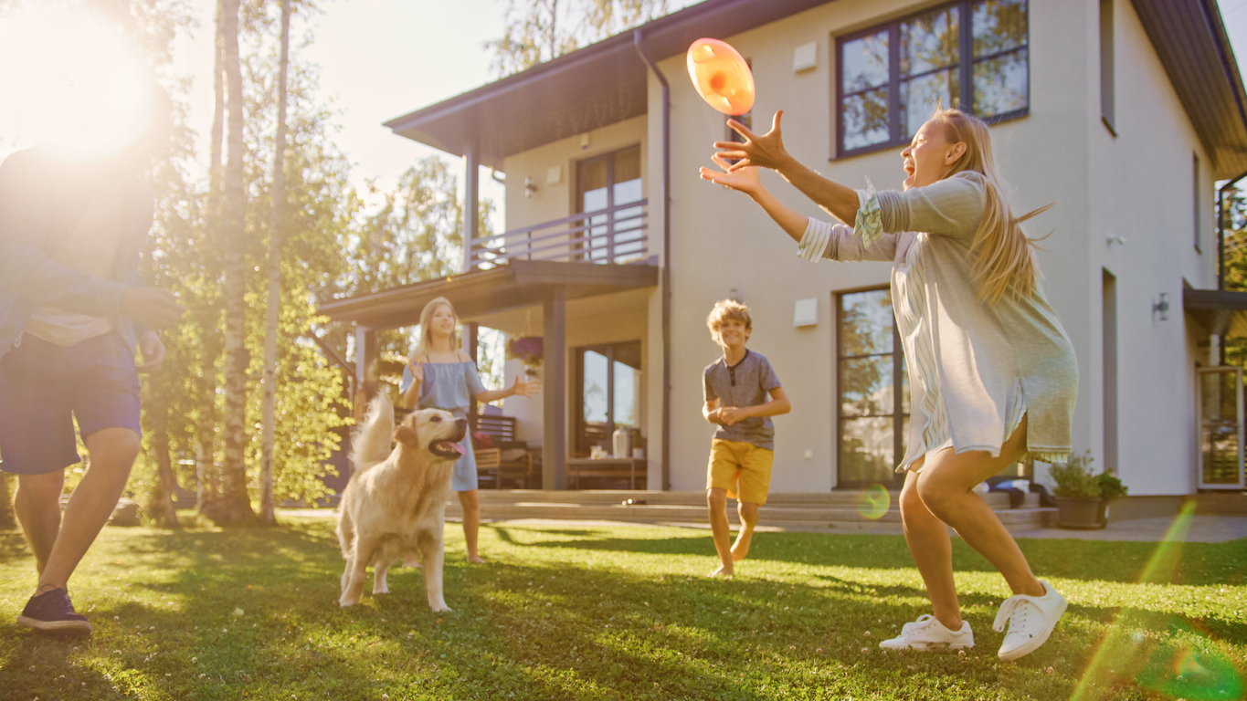 A family playing Frisbee on the lawn with their dog.