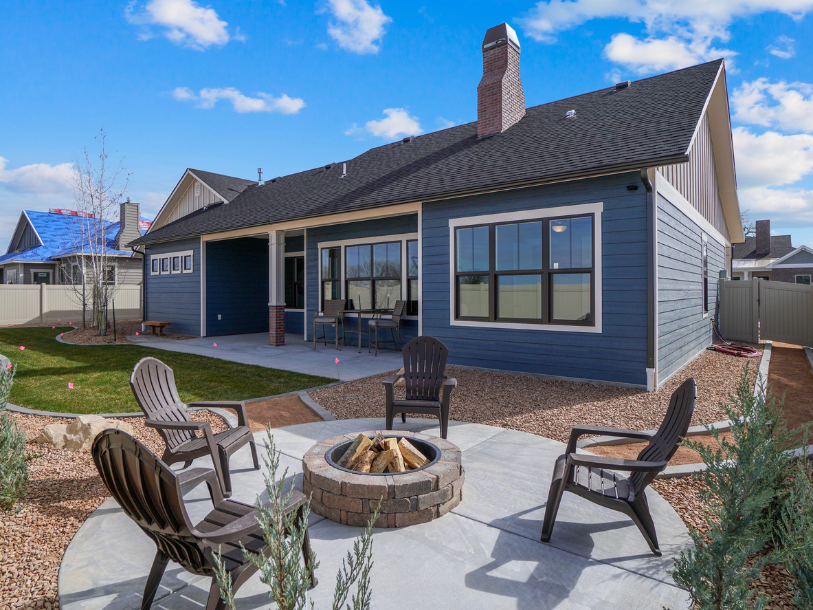 A stone fire pit behind a blue house.