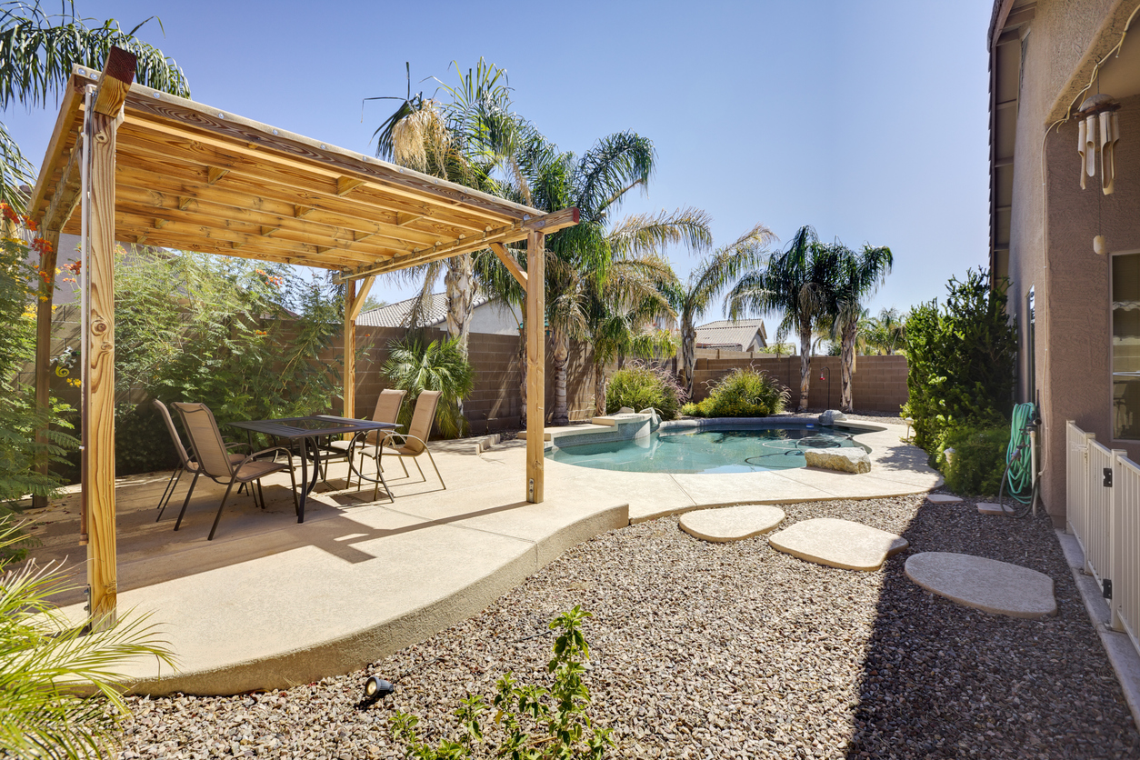 A backyard with a wooden pergola and small pool.