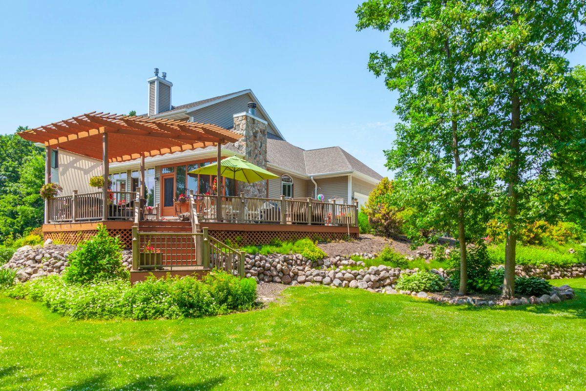 A view of a large home with a pergola.