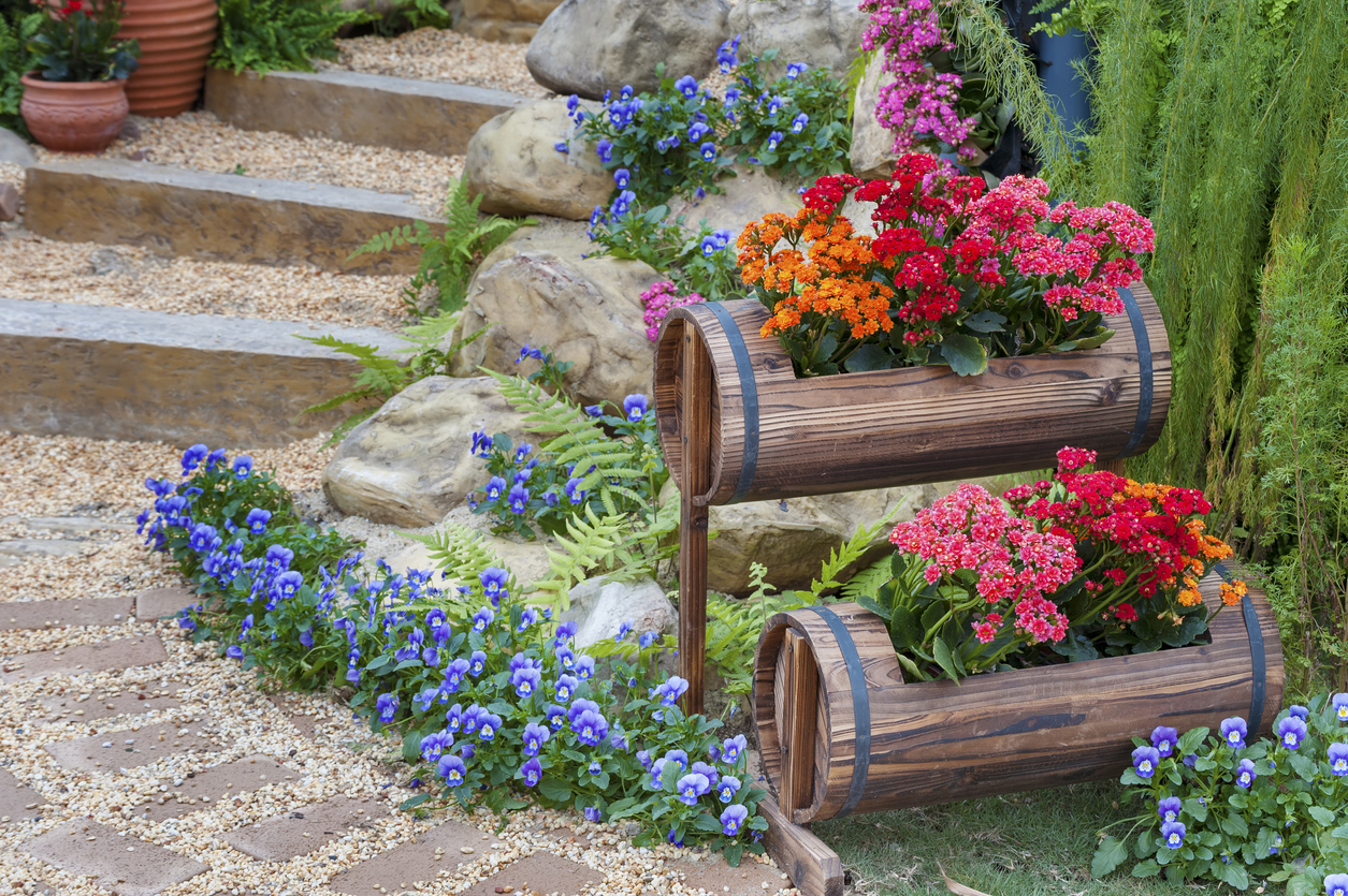 Bright flowers in container garden made with wooden barrels.