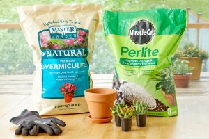 Bags of commercial vermiculite and perlite on a table with a pot and some succulents.