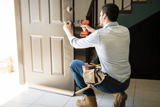 A man installs a brown door in a house.