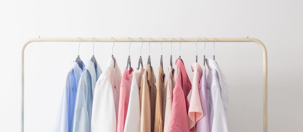 Women's pastel blouses hanging on an closet rack.