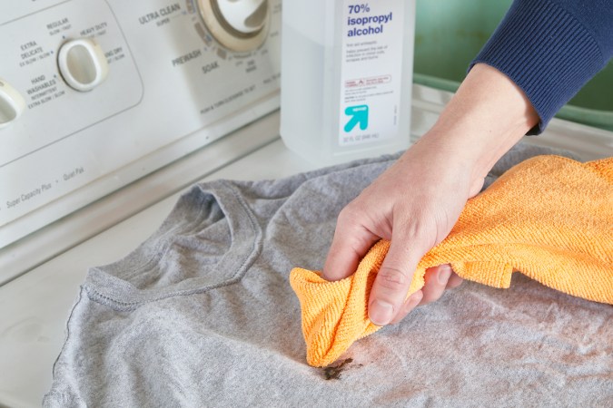 Woman applies rubbing alcohol to a caulk stain on clothing.