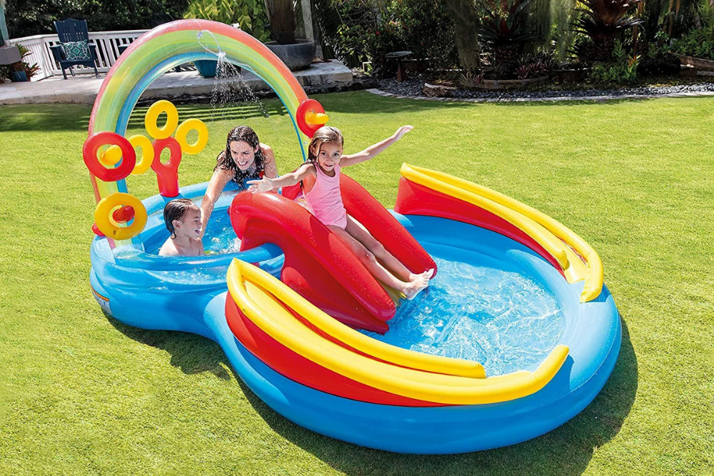 2 kids and an adult enjoying an inflatable water slide in the garden