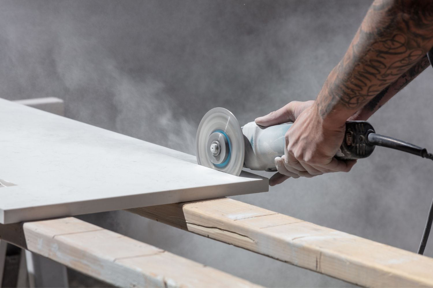 A worker uses a power tool to cut a slab of quartz.