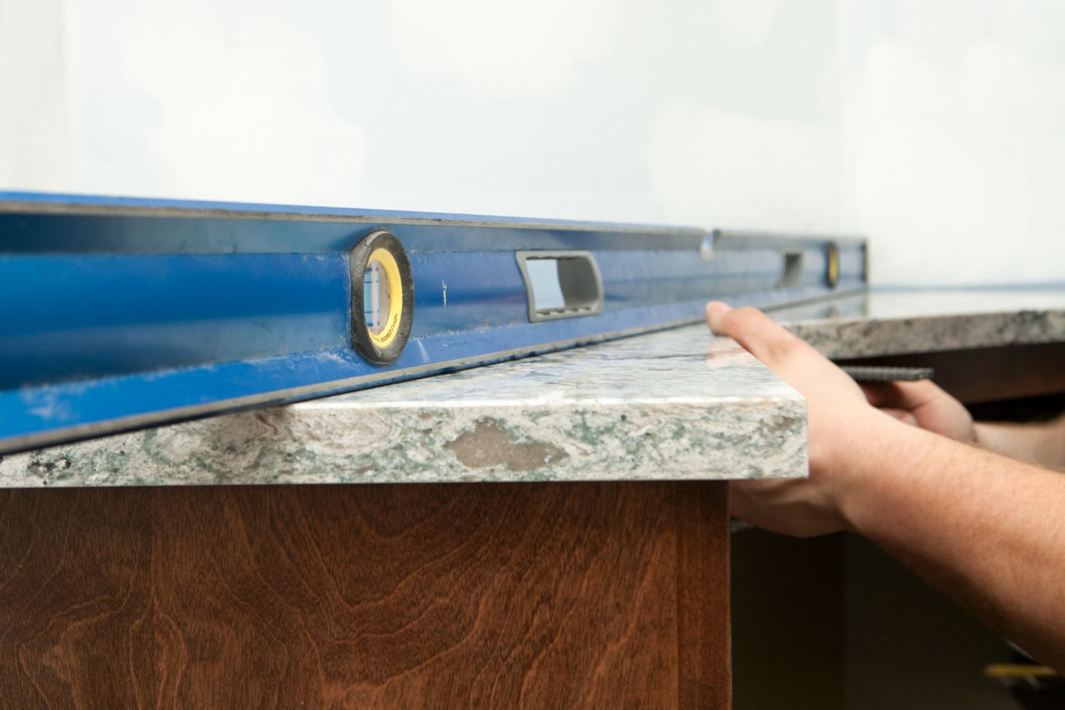 A worker installs a quartz countertop with a level.