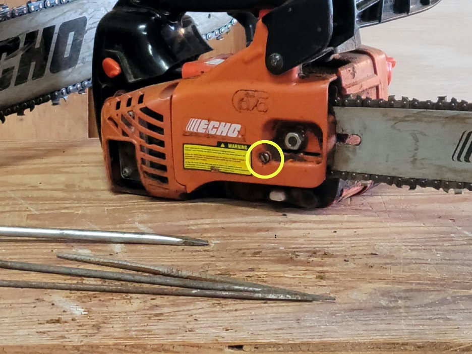 An orange chainsaw sitting on top of a wood work table.