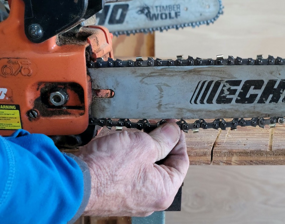 Man tests tension on a chainsaw chain.