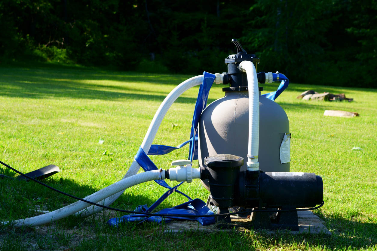 A pool heater sits on a grassy lawn.