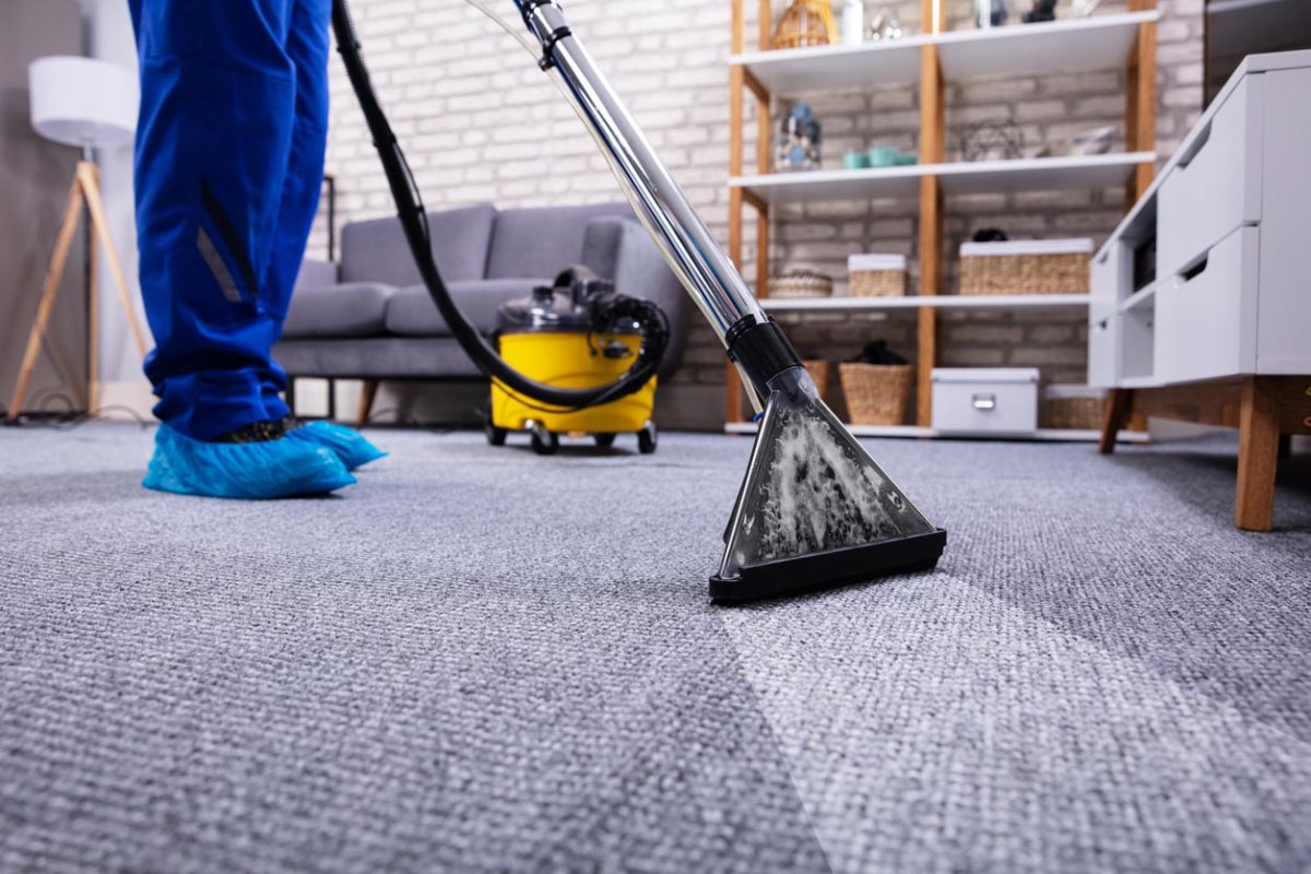 A close up of a carpet cleaner in use on a grey carpet.