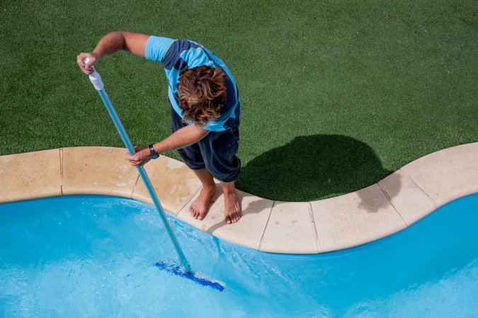 A worker cleans a swimming pool.