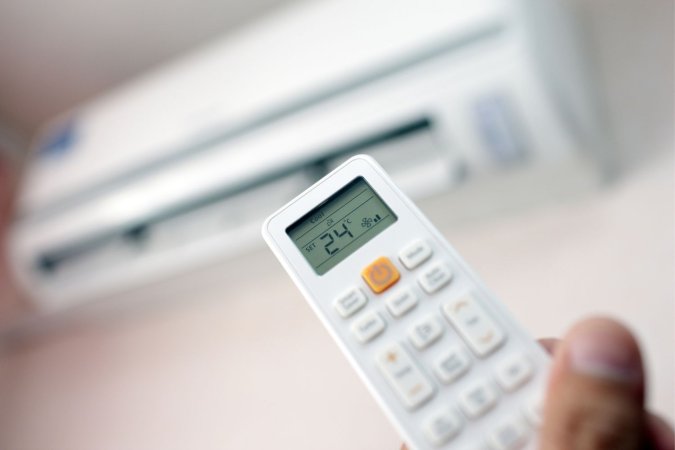 Person using remote for one of the Best Energy Efficient Air Conditioners