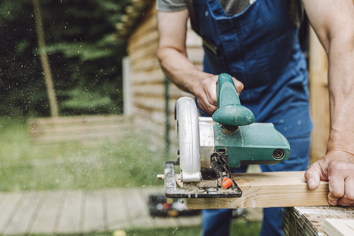 A DIYer using a circular saw to make a cross cut on a 2x4 board.