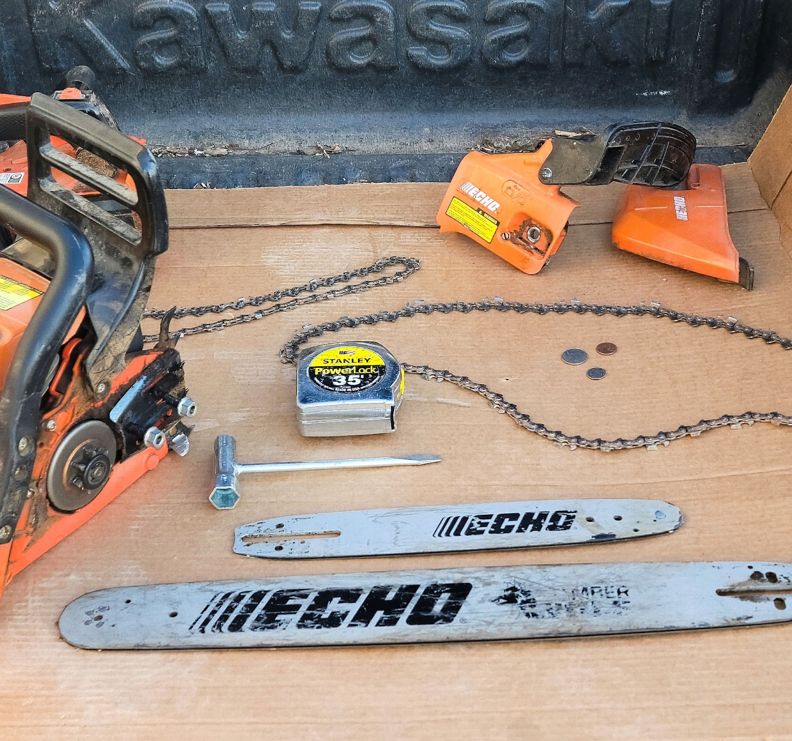 Chainsaw, chainsaw bars and chains, and a tape measure laid out on a table.