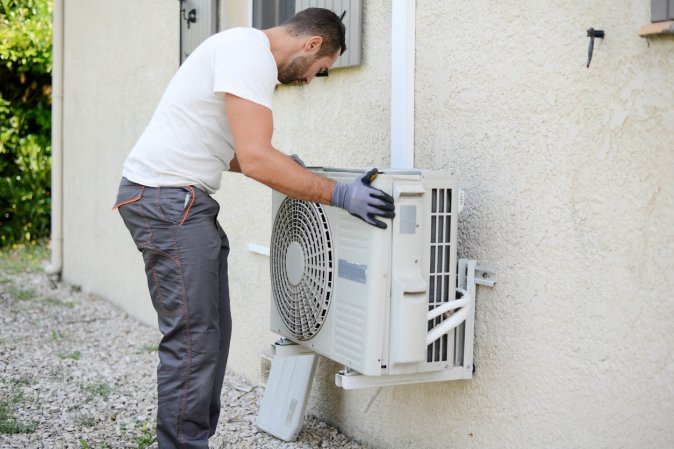 A worker installs a mini split outside.