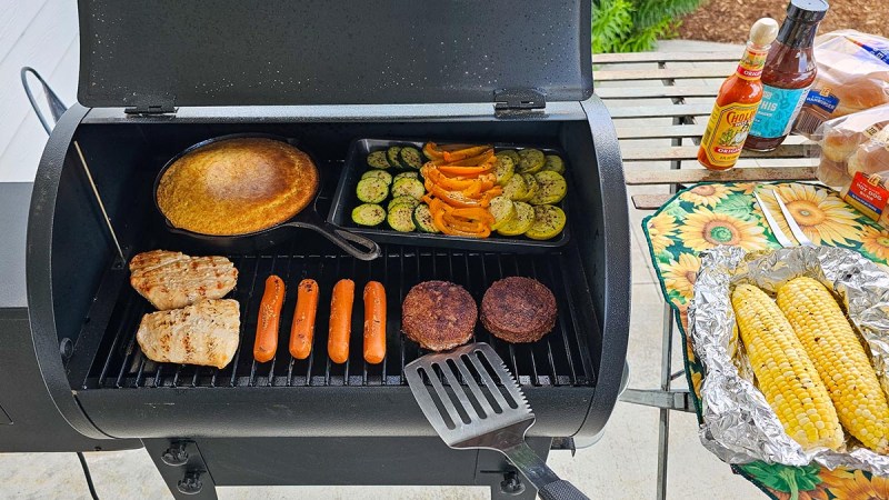 The Traeger Tailgater Portable Wood Pellet Grill open to show an array of food during testing.