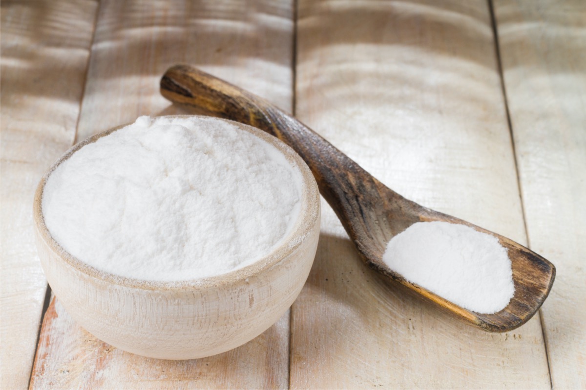 Bowl of baking soda with a wooden spoon nearby.