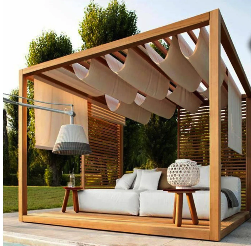 Gorgeous pergola with a white puffy couch underneath, and white cloth hanging from the slats overhead.