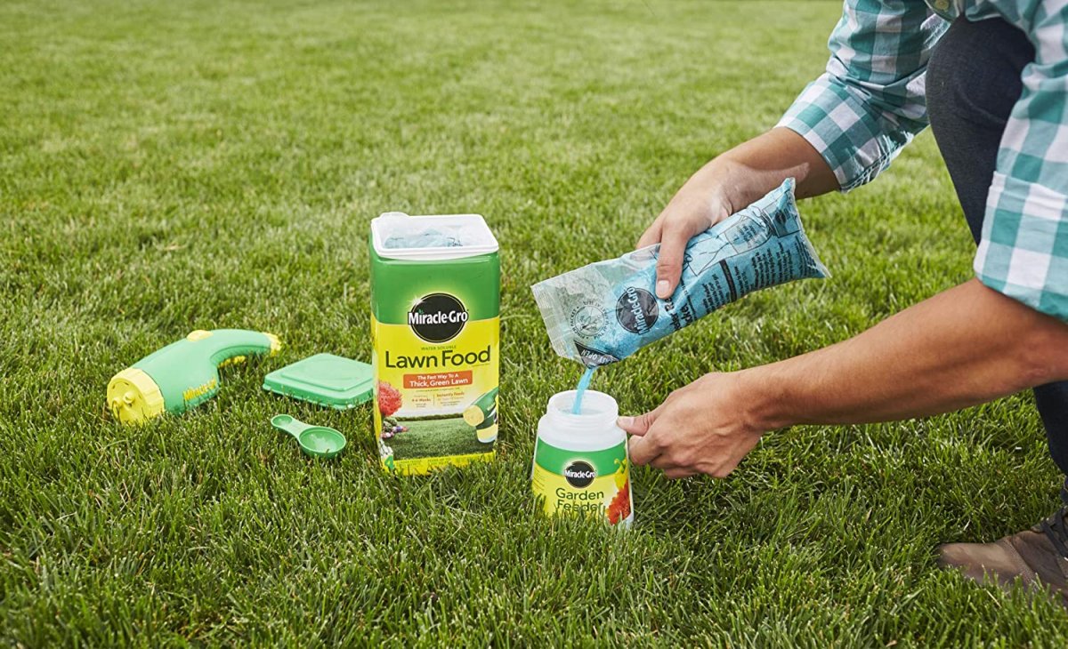 Someone pouring fertilizer into a Miracle-Gro container on a green lawn