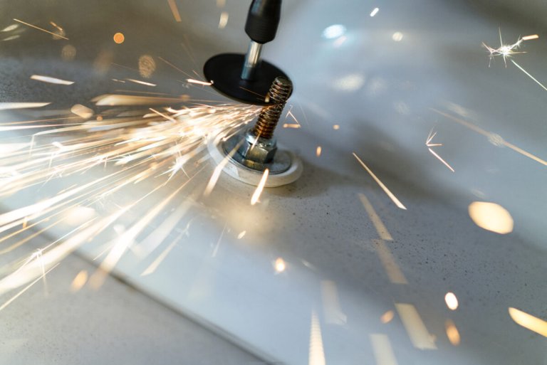 Using a drill to cut a screw with flashes of fire.