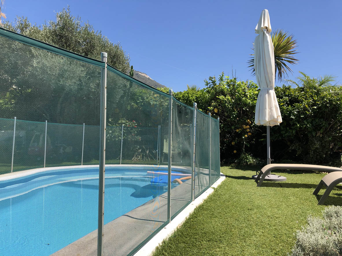 A tall mesh fence surrounding an inground pool.