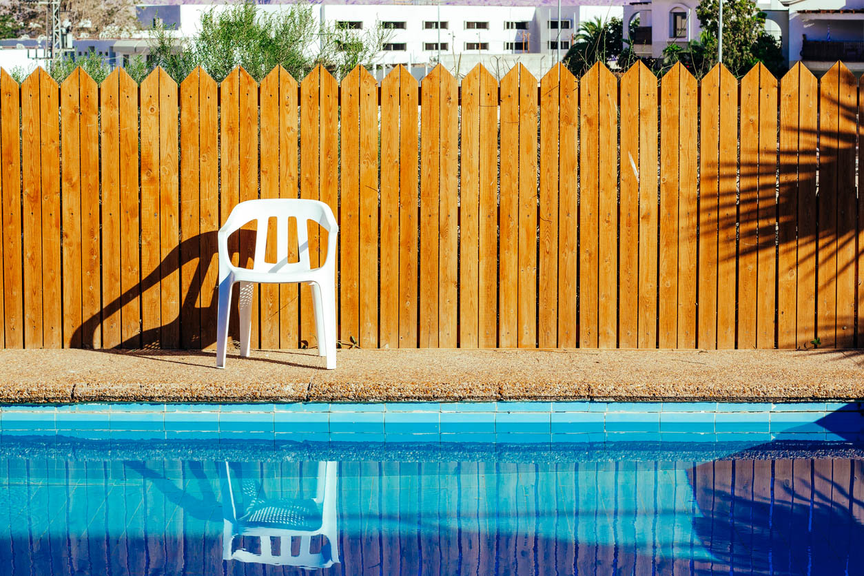 A wood privacy fence surrounds an inground swimming pool.