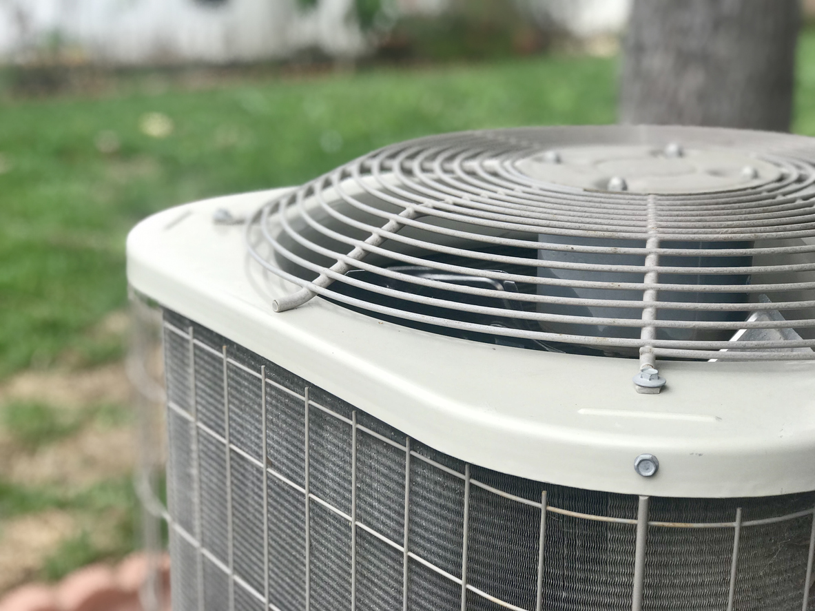 Close view of an air conditioning compressor outdoors.