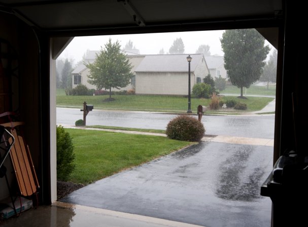 View from inside a garage of the driveway and the rainstorm outside.