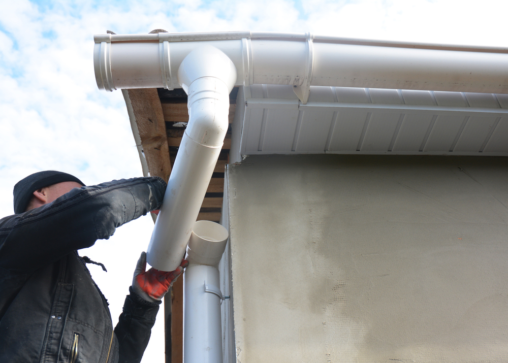 A contractor is working on a home's fascia, soffit, and gutters.