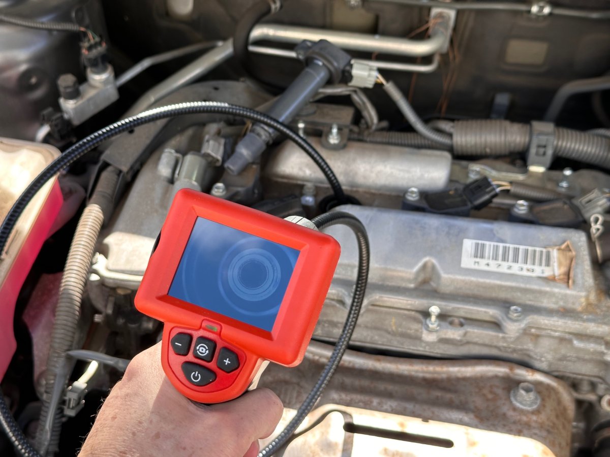 A person holding the Ridgid’s Micro-CA-25 over a car's engine.