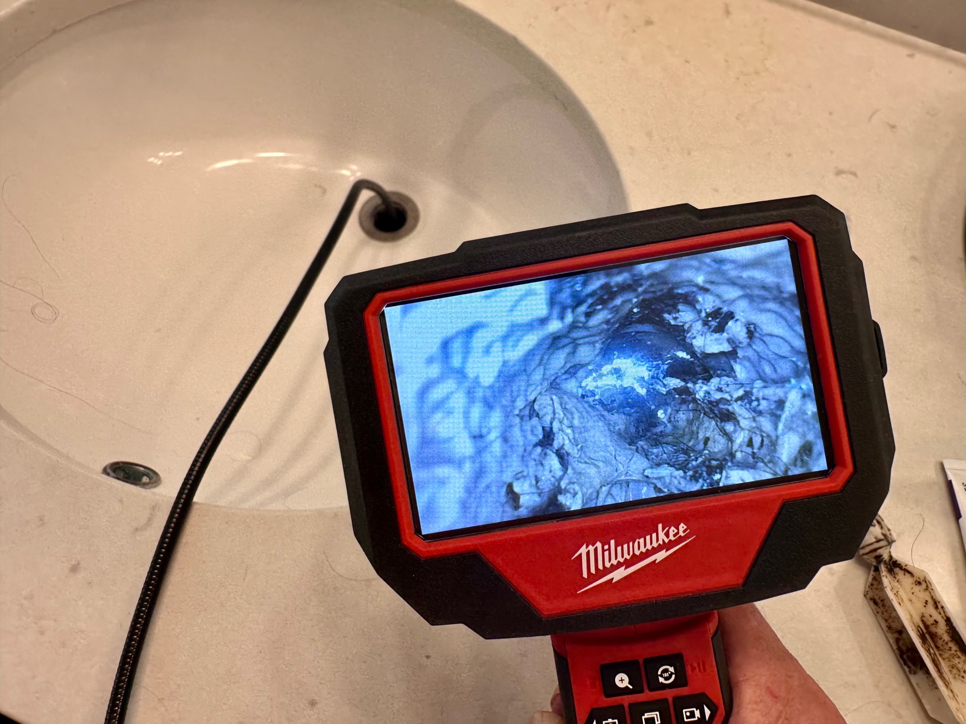 a man holding Milwaukee M12 M-SPECTOR Inspection Camera Kit over a wash-basin
