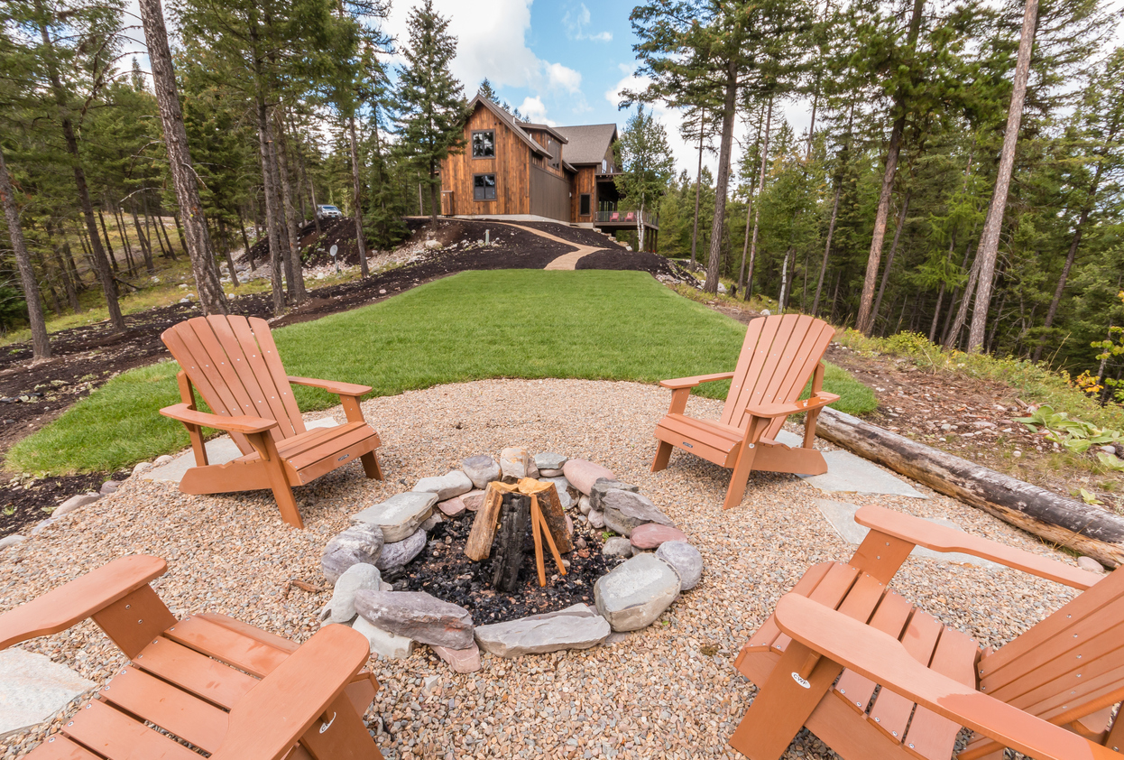 Circular fire pit area in the back of home in the forest.