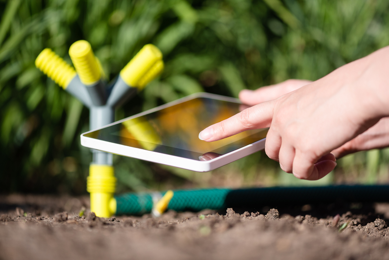 A gardener with a digital tablet using a smart garden application concept. Watering system.