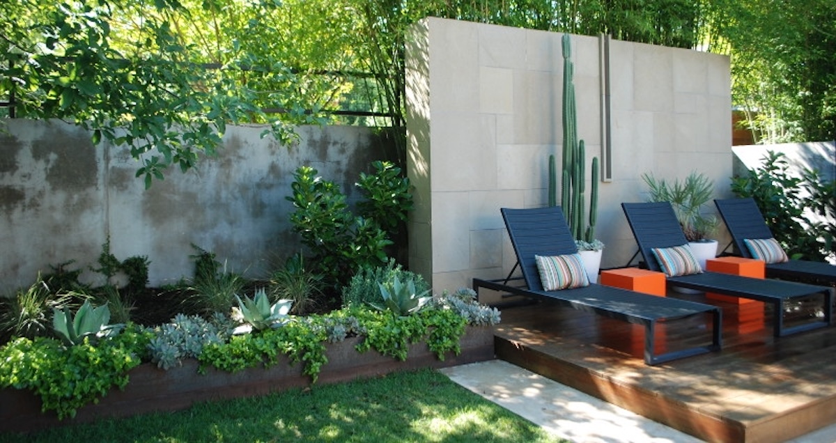 An outdoor patio area with pool chairs and green flower bed.