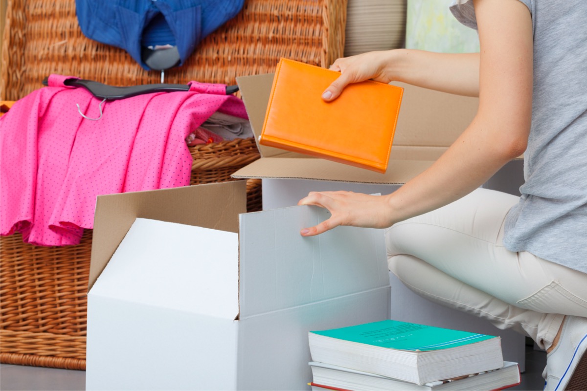 Woman putting books and clothes in a box for donations.