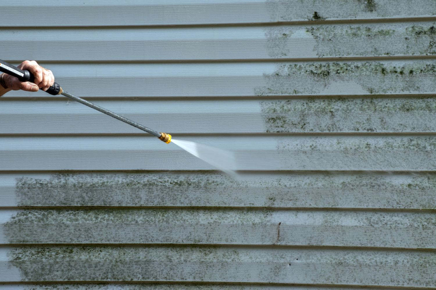 A close up of siding being power washed.