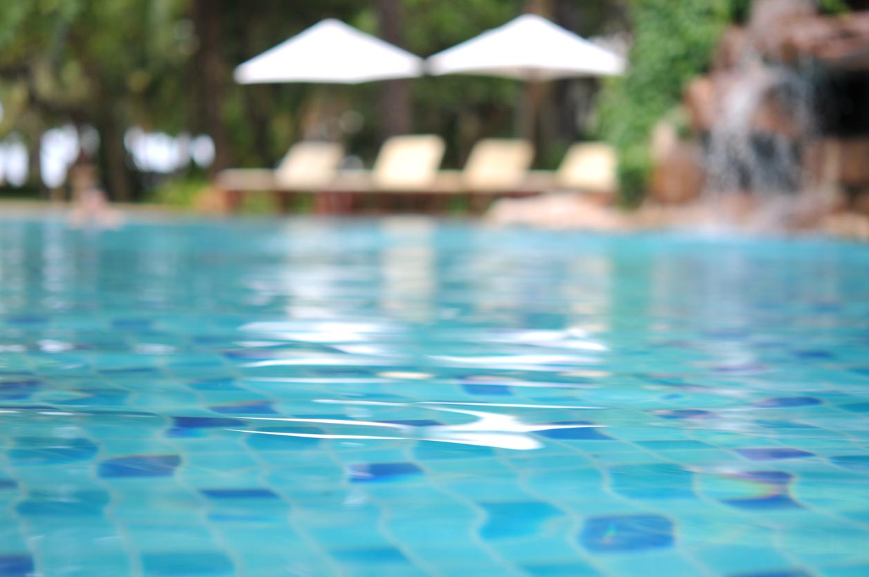 A sparkling pool with lounge chairs and umbrellas in the background.