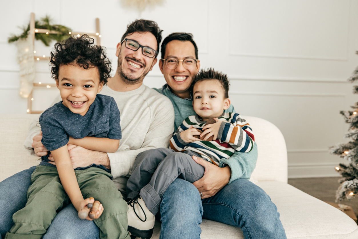 Same sex couple with two beautiful children on their laps