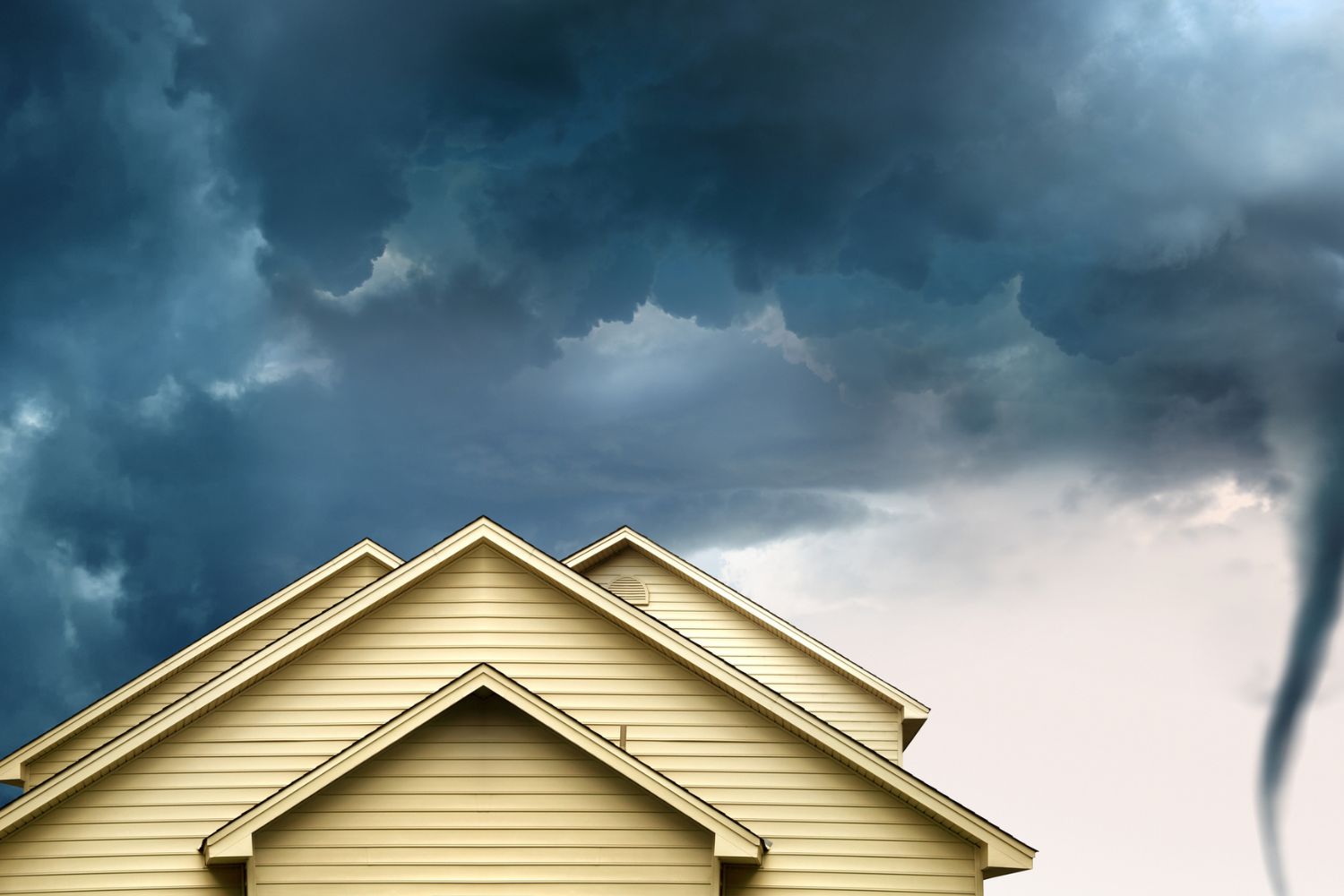 A view of a tornado in the distance and a home's roof.