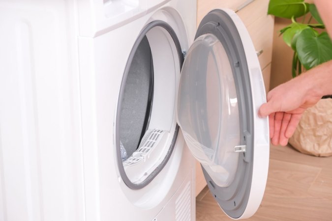 A close up of a person opening the door of a washing machine.