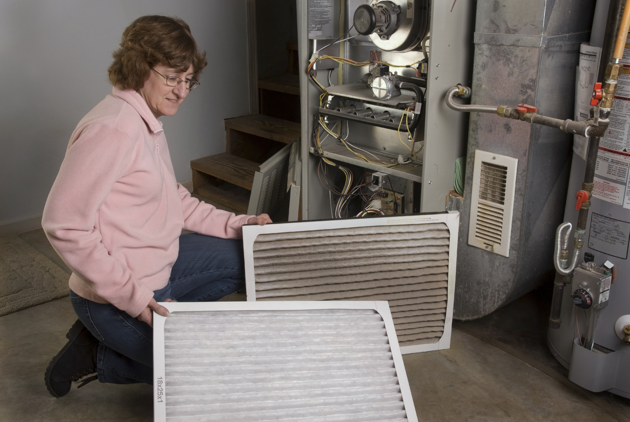 Woman changes the filters in her home furnace.