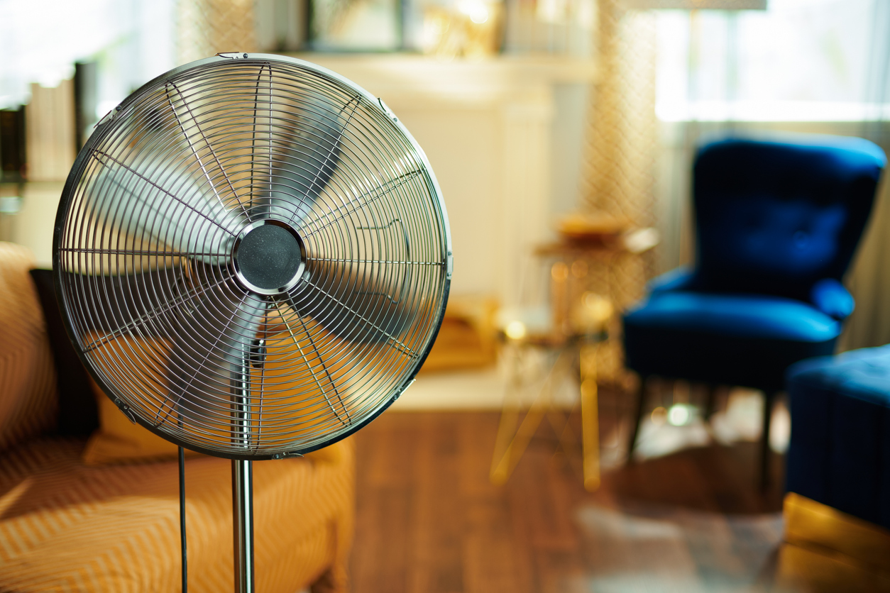 An upright metal fan in a living room.