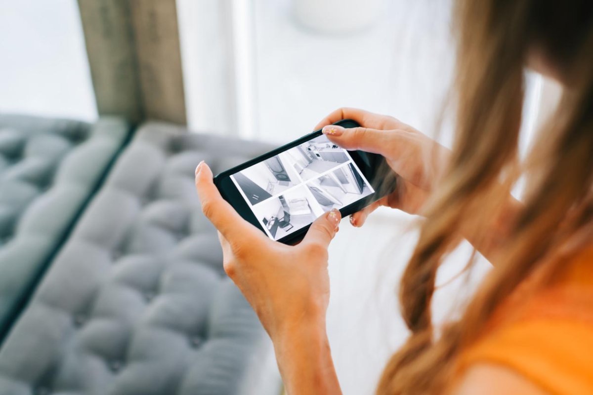 Woman looks at phone screen and watches security camera footage.